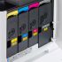 A close-up view of the toner cartridges inside a Kyocera printer. The four cartridges are labeled with their colors: yellow, cyan, magenta, and black.