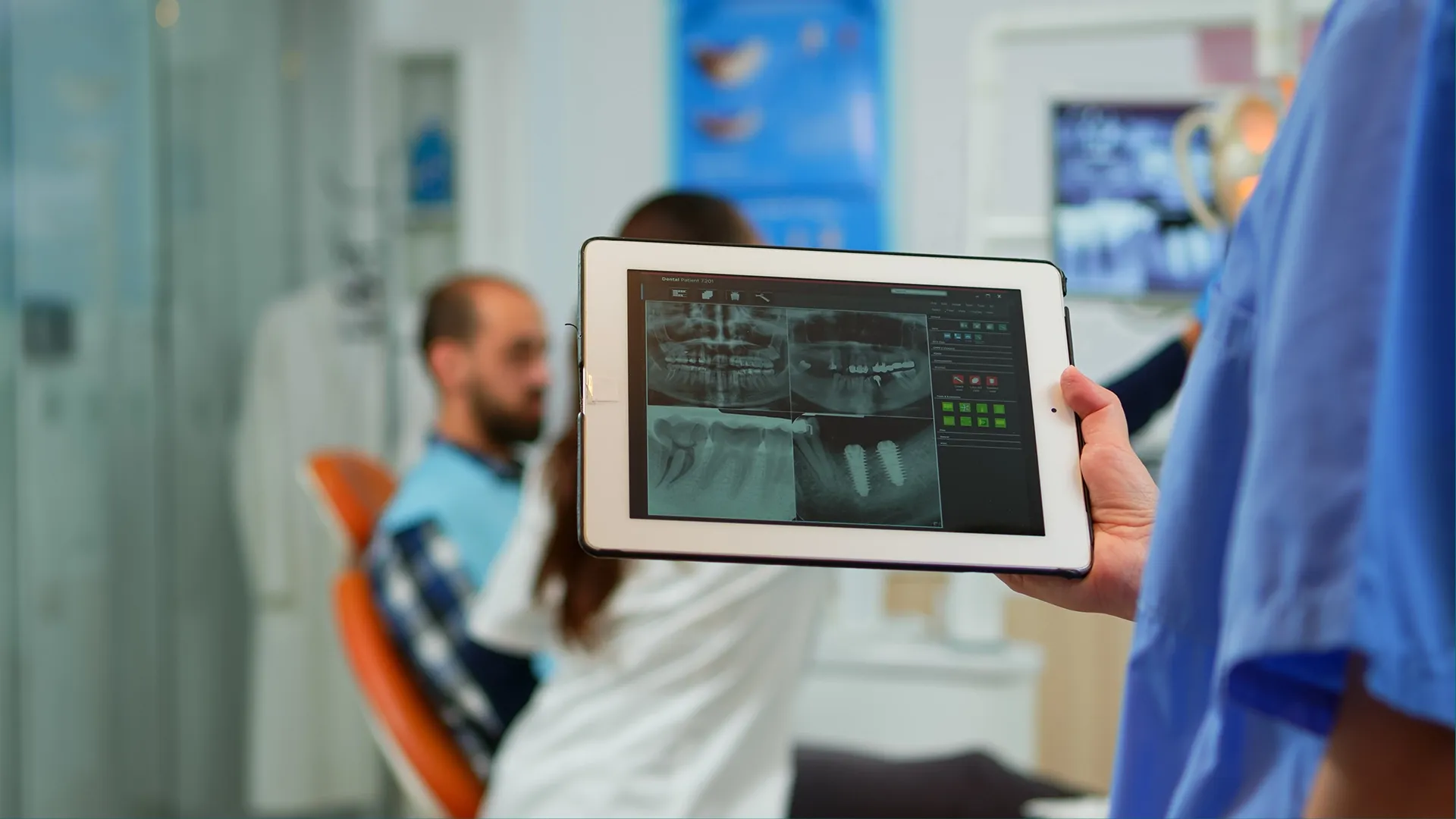 Dental professional holding a tablet displaying patient X-rays and implants, demonstrating modern, secure digital records via Elevation Technology.