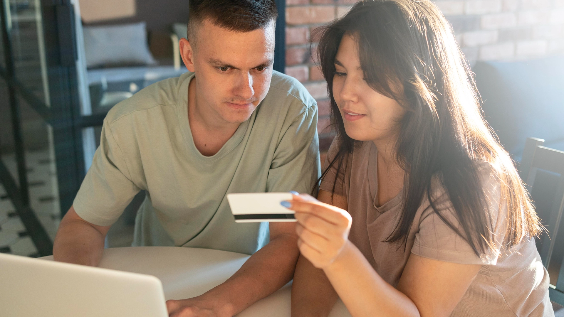 Credit union members, a man and a woman, securely reviewing their credit card details online using a laptop and the trusted Elevation Technology platform.
