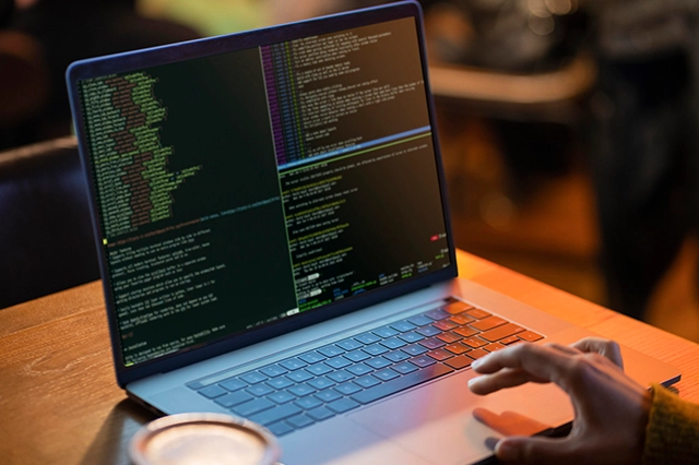  A laptop displaying code with a hand typing on the keyboard, highlighting programming, software development, and IT solutions.
