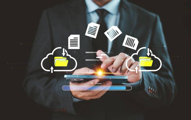 A business professional is holding a smartphone, with two glowing cloud icons on either side. Files and folders are shown being transferred between the clouds and the phone, symbolizing data migration and cloud storage.