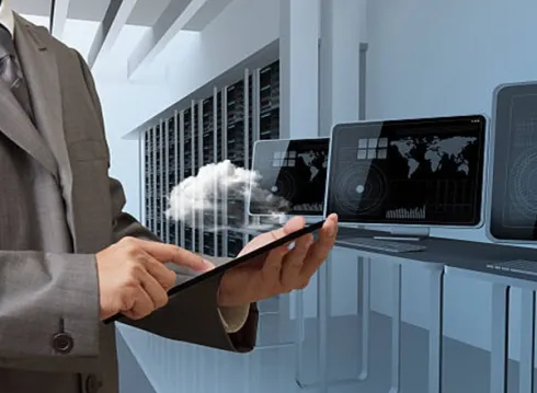 Businessman managing cloud computing services on a tablet in a data center.