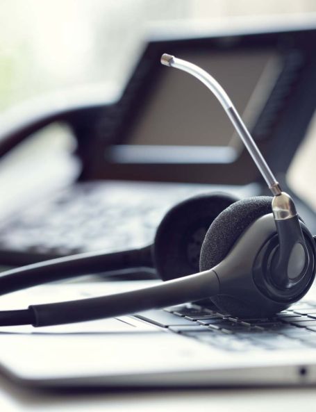Mobile close-up of a professional headset on a laptop keyboard, representing unified communications, cloud hosting, business email, and cloud email by Elevate Technology.