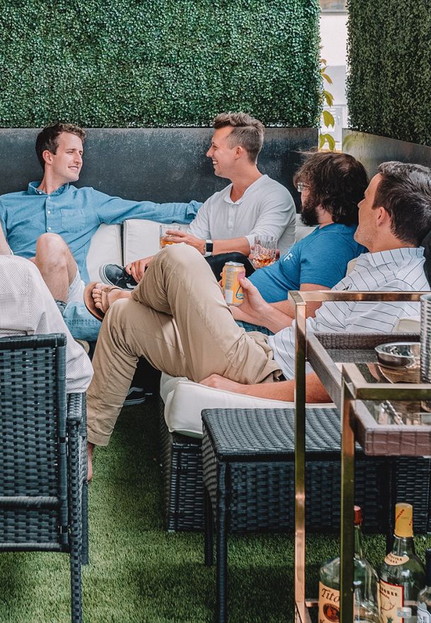 A group of Elevate Technology team members relaxes and socializes on an outdoor patio, enjoying drinks after work.