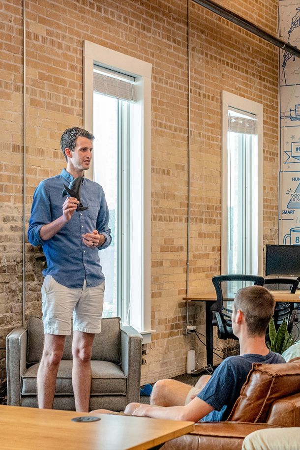 An Elevate Technology team member standing and presenting to a colleague in a casual office setting.