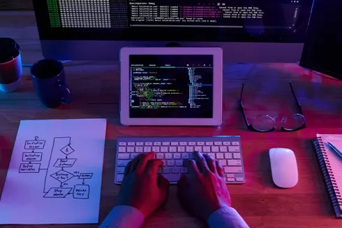 A developer's desk with a laptop, tablet, and keyboard, highlighting programming, software development, and IT solutions.