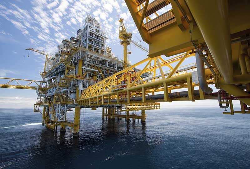 A powerful image for Elevate Technology, showing a large offshore oil rig or gas platform complex rising from the ocean. 