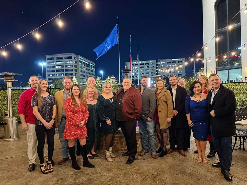 The Elevate Technology team gathered for a company social event outdoors at night, standing together and smiling in holiday or formal attire.