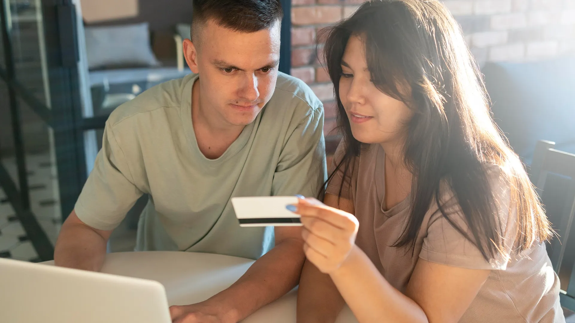Credit union members, a man and a woman, securely reviewing their credit card details online using a laptop and the trusted Elevation Technology platform.